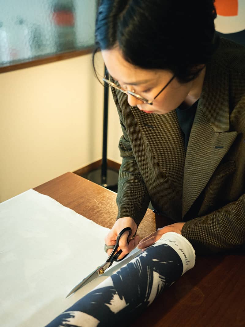 Asami cuts cloth she designed