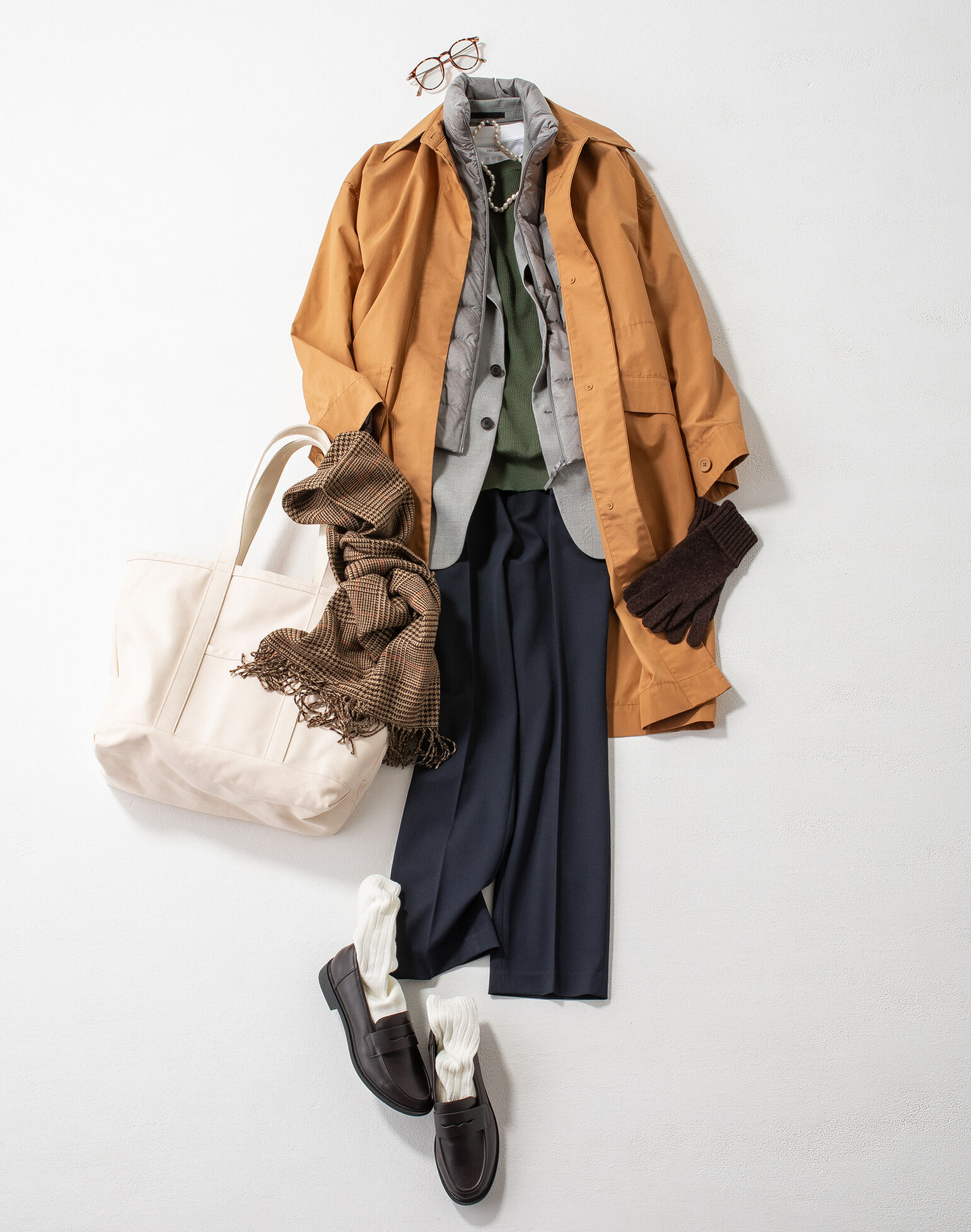 ベージュのコットンロングコートにオーバーサイズクルーネックベストを合わせたコーデ