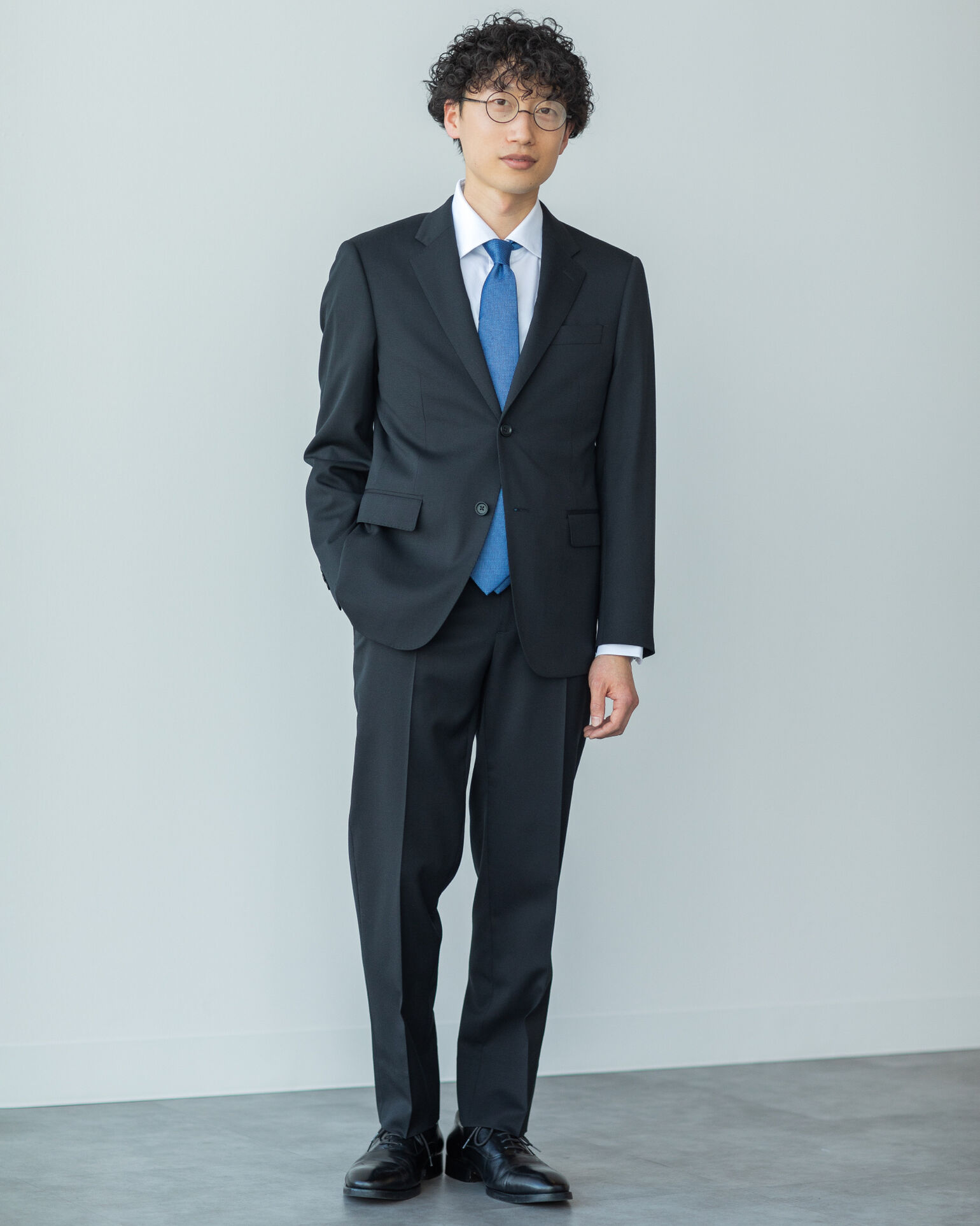 ポケットに手を入れてこちらを見つめるスーツを着たYoshihikoさんの画像