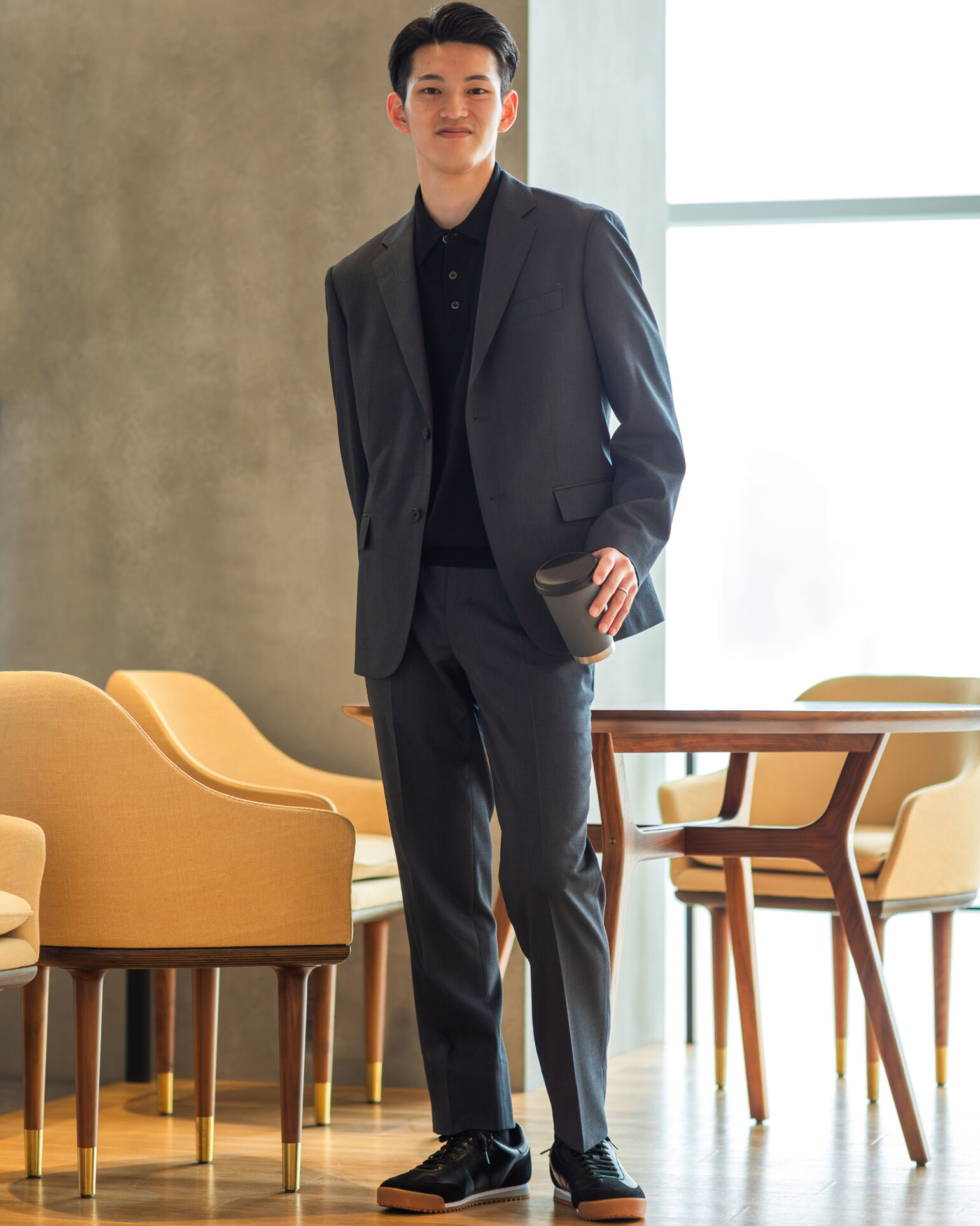 コップを持ってこちらを見つめるスーツを着たShuiさんの画像