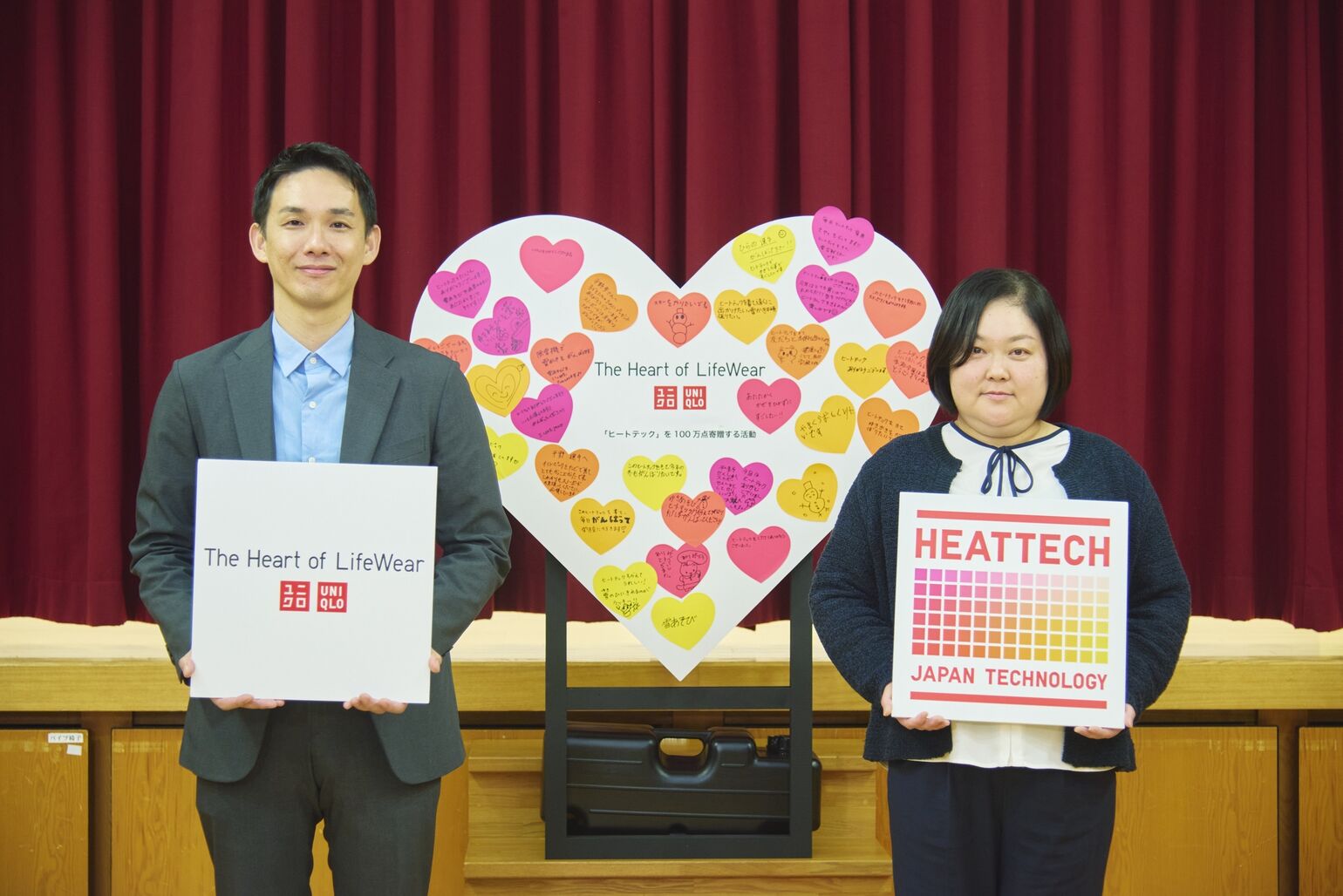 「The Heart of LifeWear」と「HEATTECH」のパネルをそれぞれ持った男女が、ハート型のメッセージボードの両脇に立っている画像